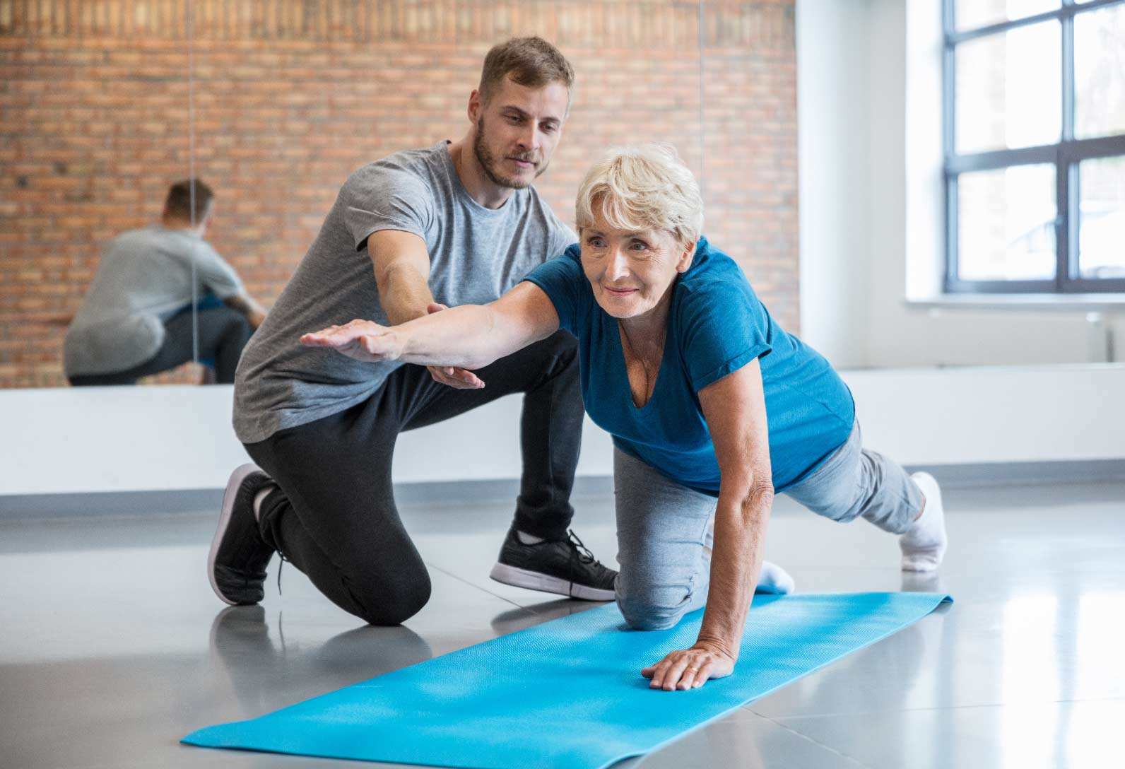 Woman guided in stretching by trainer